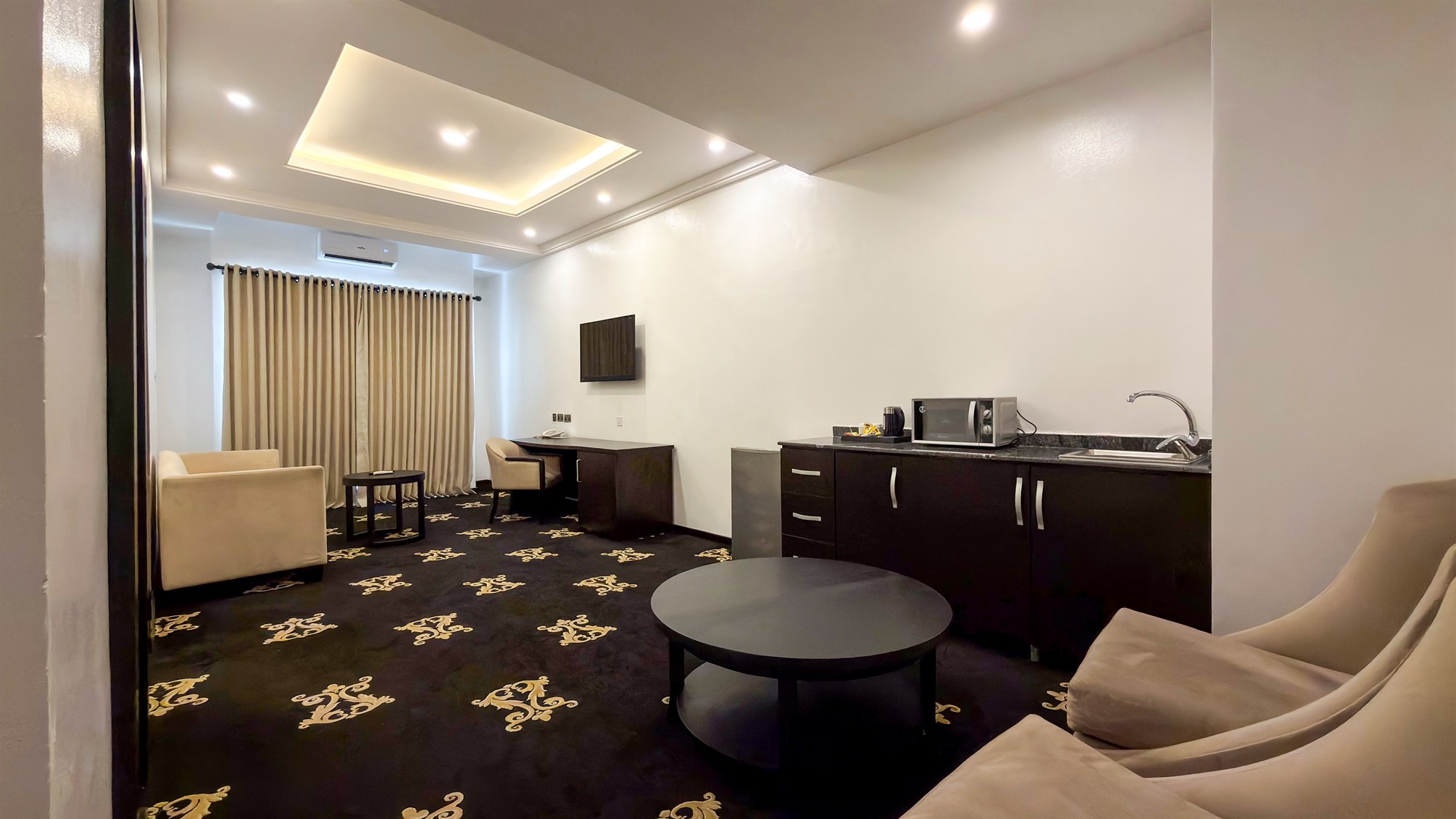 A suite living room with soft seating, a round table and a kitchenette